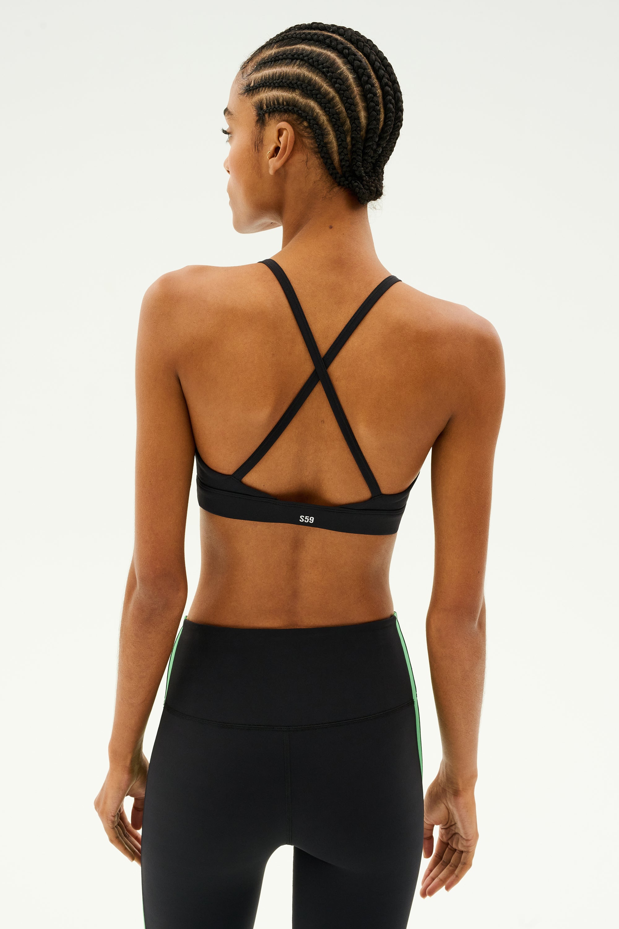 A person is seen from behind wearing the SPLITS59 Theo Rigor Bra in black and leggings, both made from ultra-luxe Rigor fabric ideal for multi-sport performance.