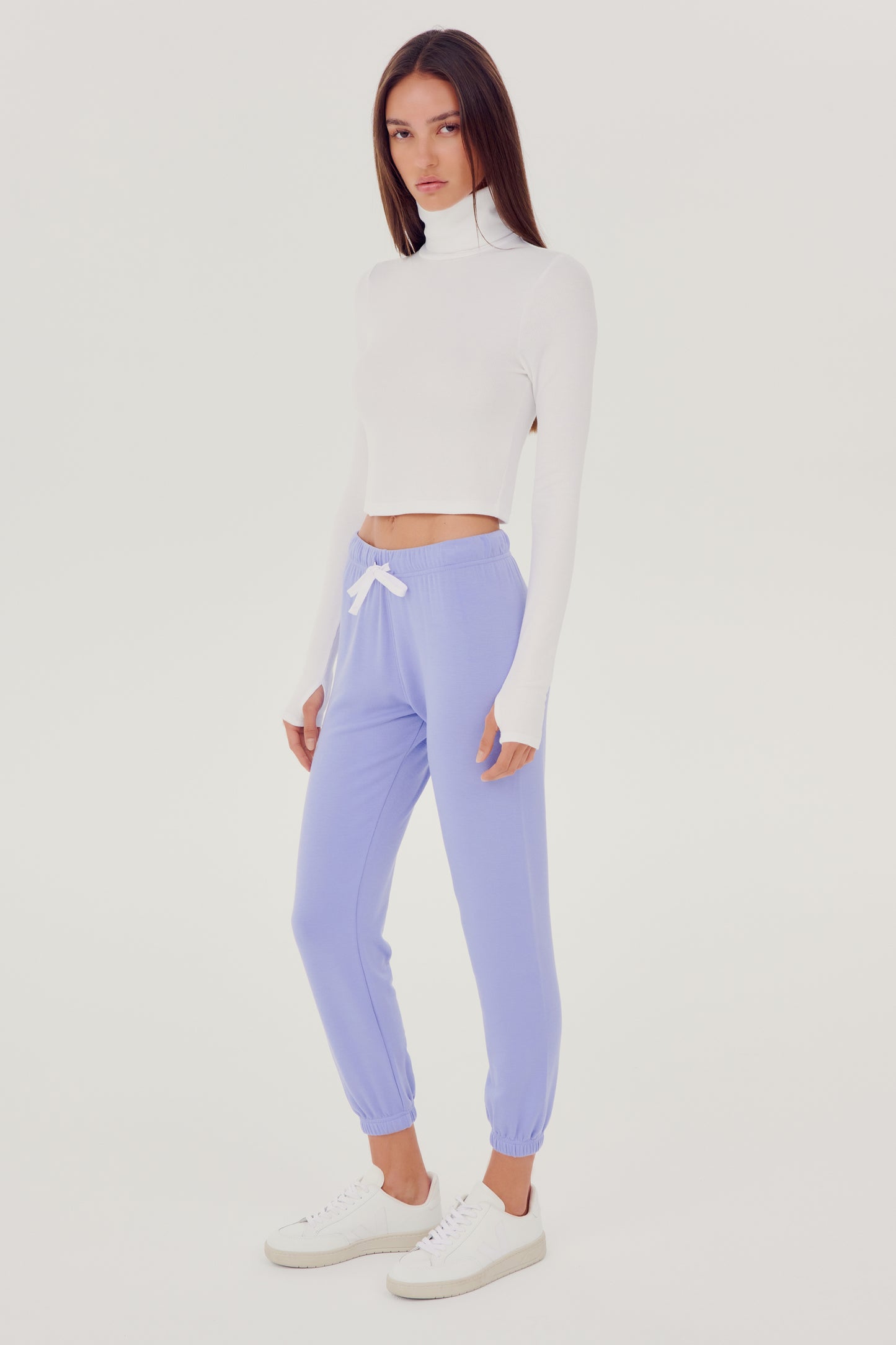 The model is wearing a white SPLITS59 Jackson Rib Cropped Turtleneck and lavender high waist leggings.