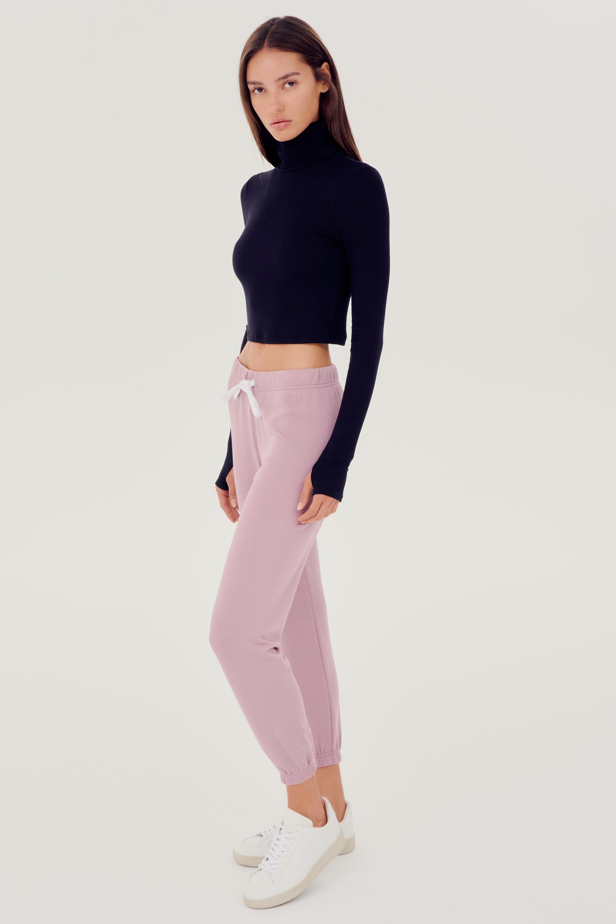 The model is wearing a black SPLITS59 Jackson Rib Cropped Turtleneck and high waist pink leggings.