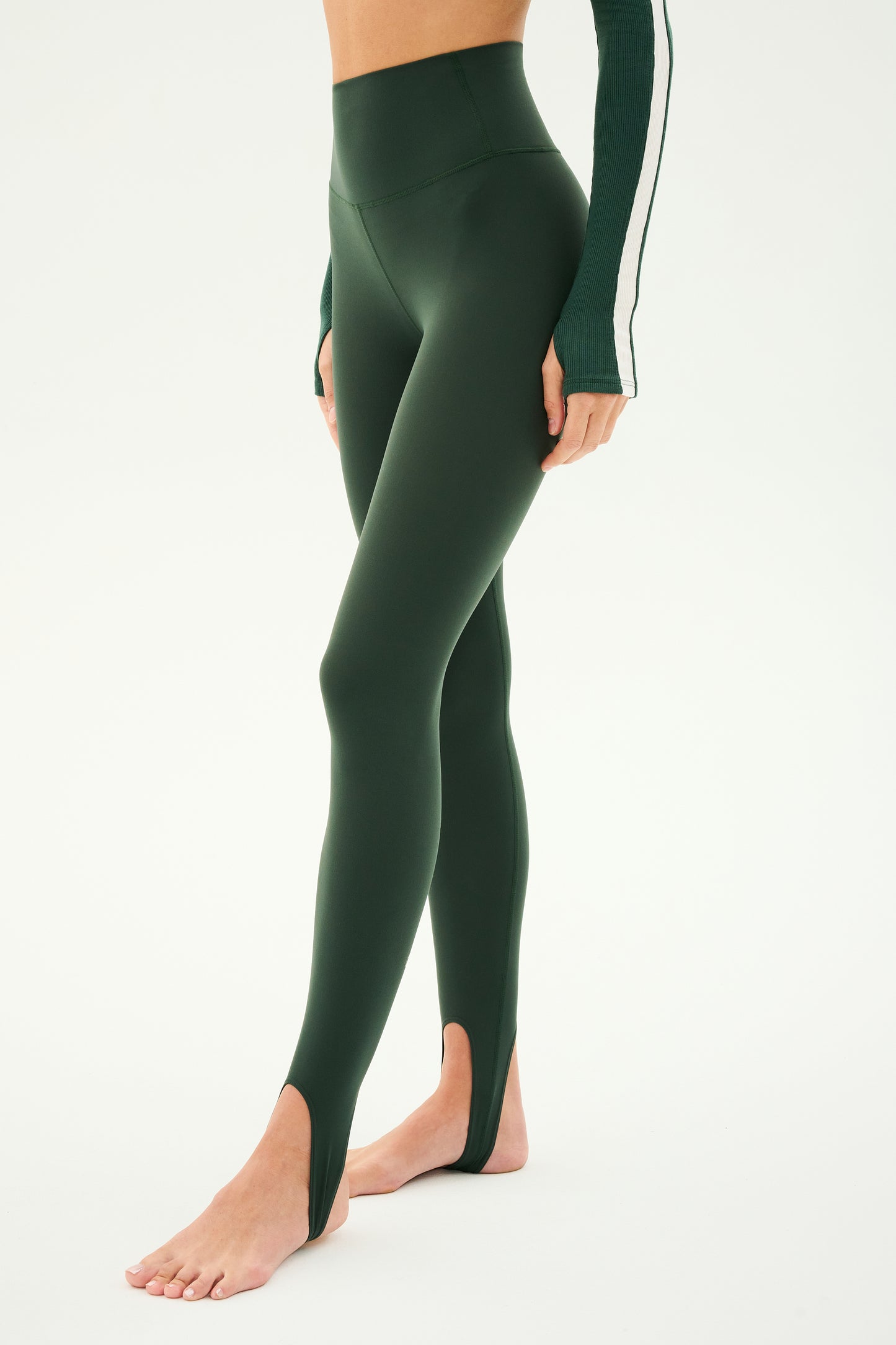 A person wearing the SPLITS59 River High Waist Airweight Stirrup leggings in Military stands against a plain background. The individual's head and feet are not visible.