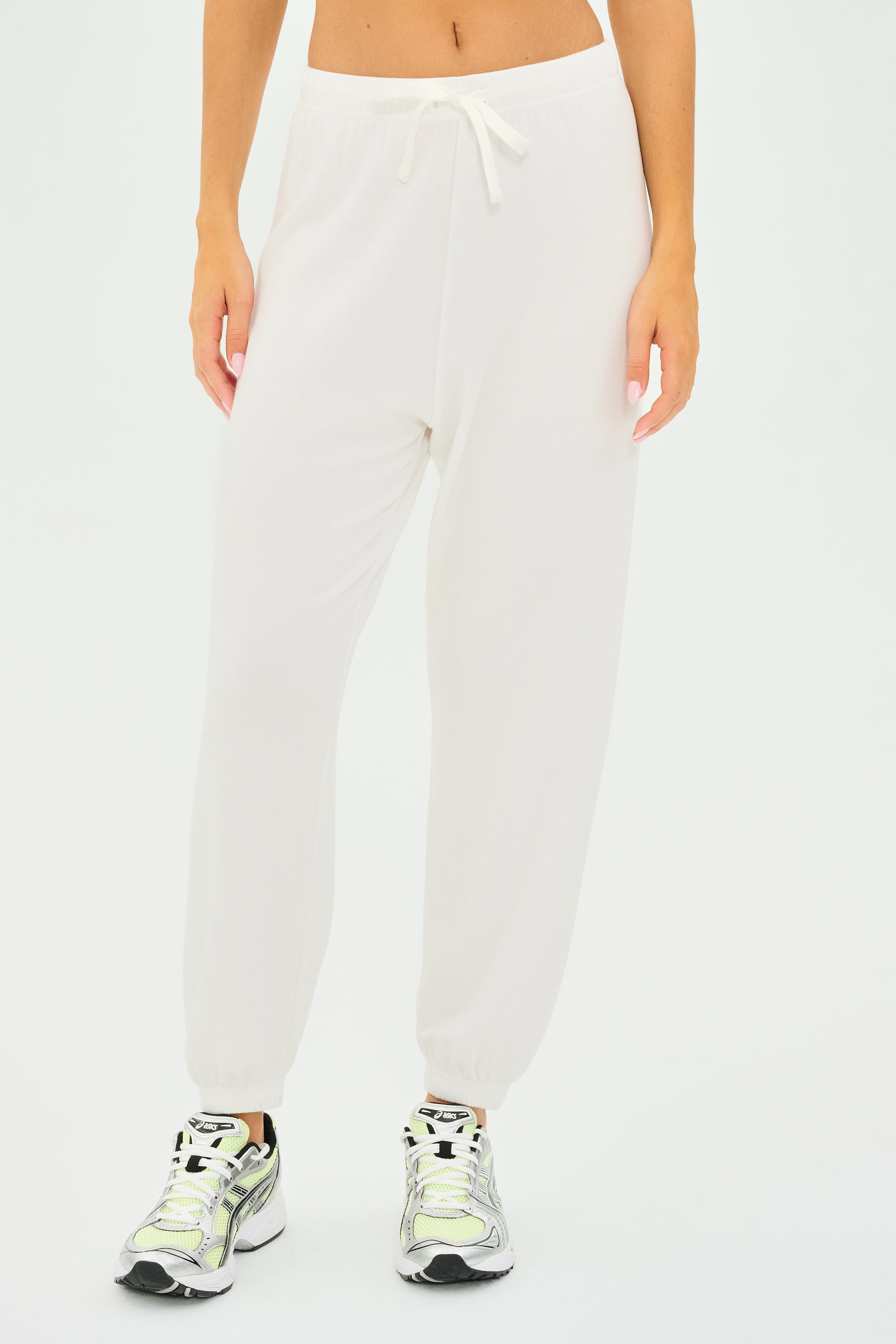 Individual wearing SPLITS59 Andie Oversized Fleece Sweatpant in white and silver sneakers against a plain backdrop.