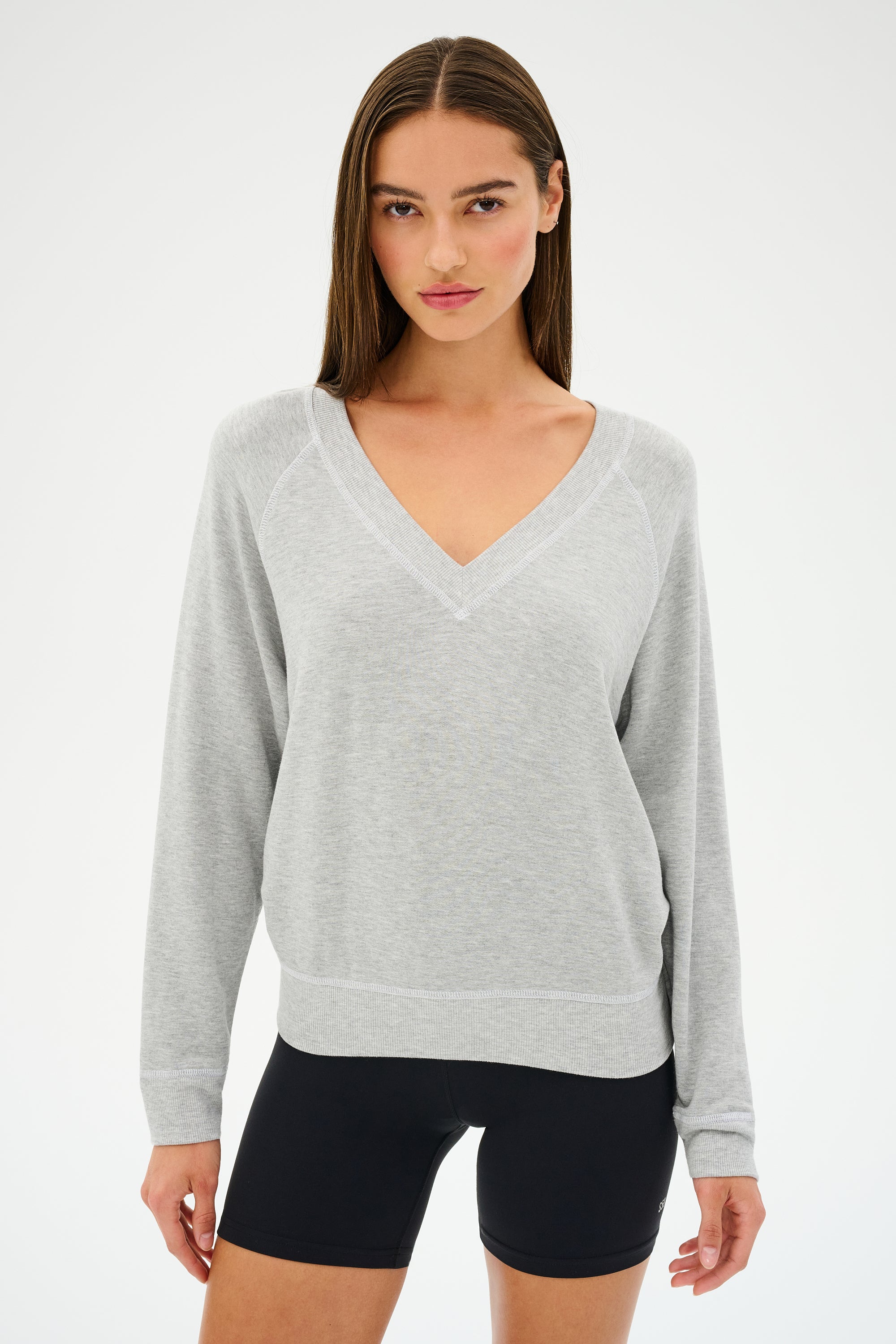 A person wears the SPLITS59 Bennie Fleece V-Neck Sweatshirt in Heather Grey/White with black shorts against a plain background. This ultra-luxe, MADE IN LOS ANGELES outfit offers comfort and effortless elegance.