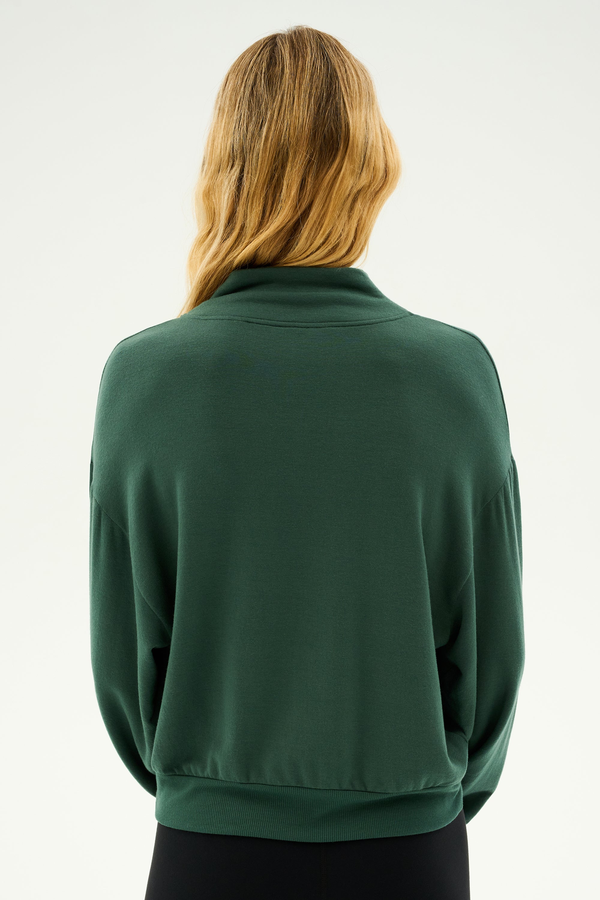 Back view of a person with long, wavy hair wearing the SPLITS59 Birdie Fleece Half Zip in Military, standing against a plain background.