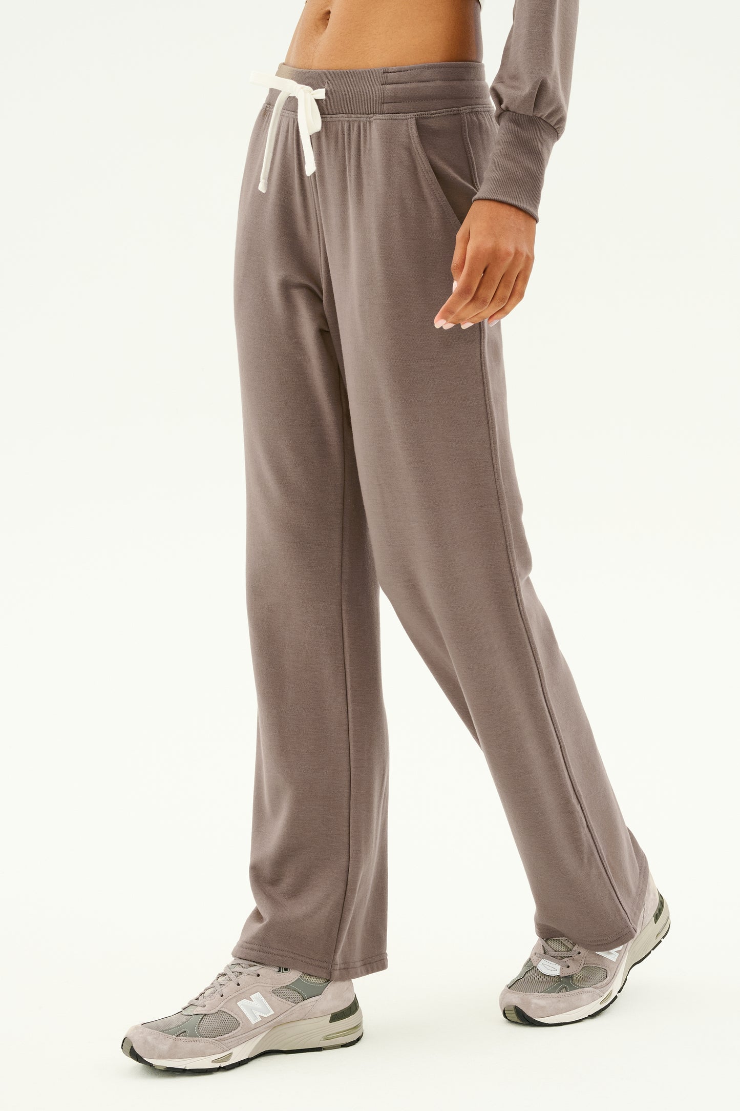 A person wearing the Raven Fleece Full Length Sweatpant in Lentil by SPLITS59 and sneakers stands against a plain background, showcasing the understated elegance of ultra-luxe fleece.