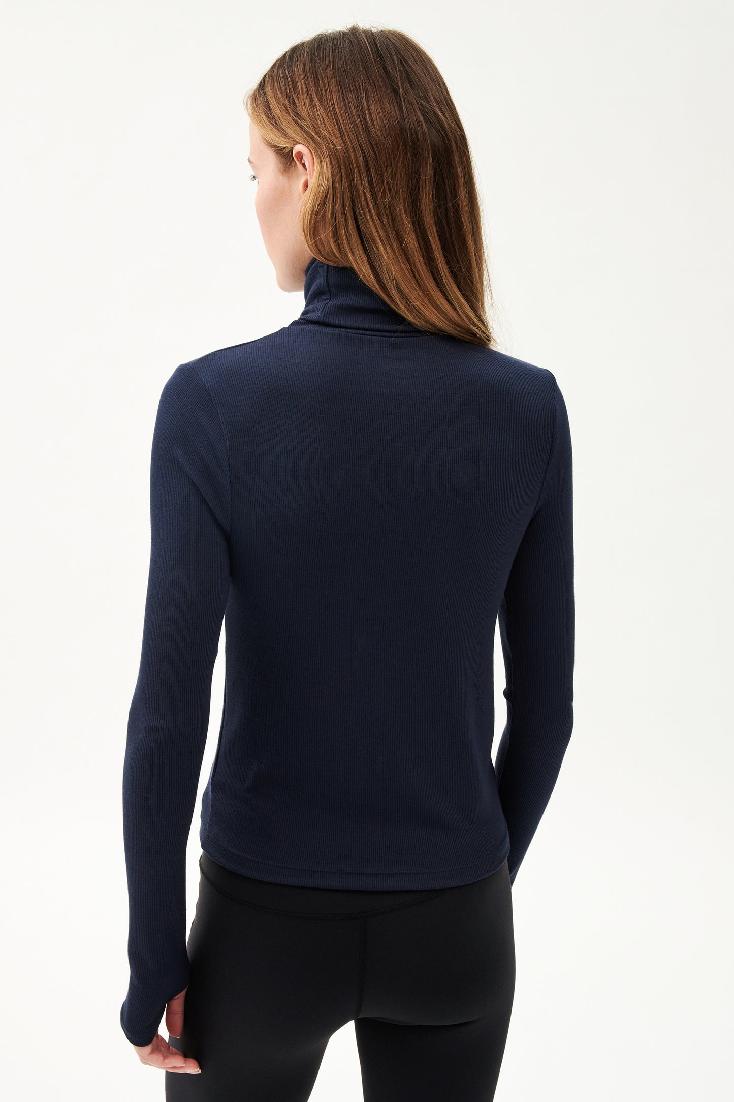 A woman in a SPLITS59 Jackson Rib Full Length Turtleneck - Indigo doing yoga.