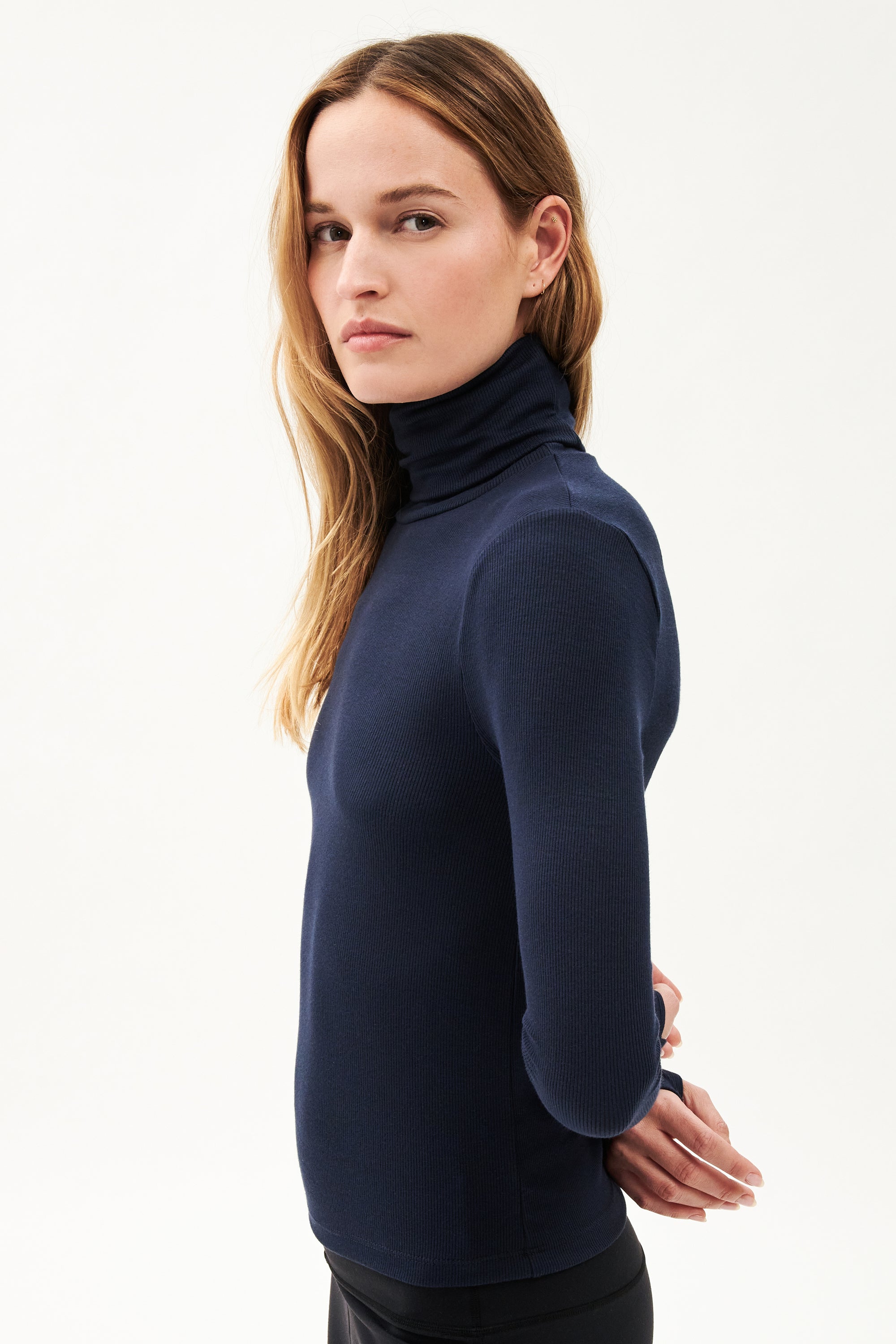 The model is wearing a navy Jackson Rib Full Length Turtleneck - Indigo top by SPLITS59.