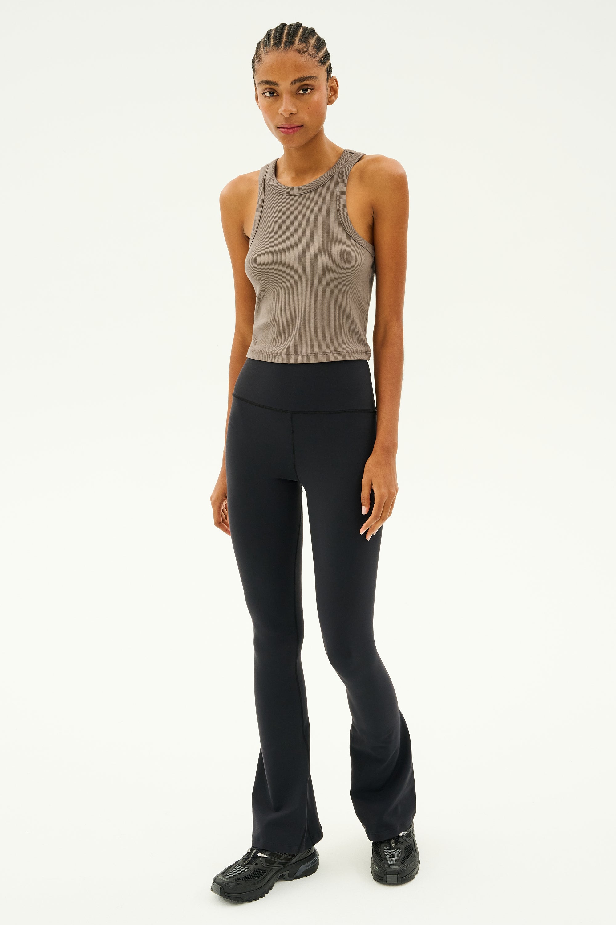 A person wearing the Kiki Rib Crop in Lentil by SPLITS59 and black pants, standing against a plain background.