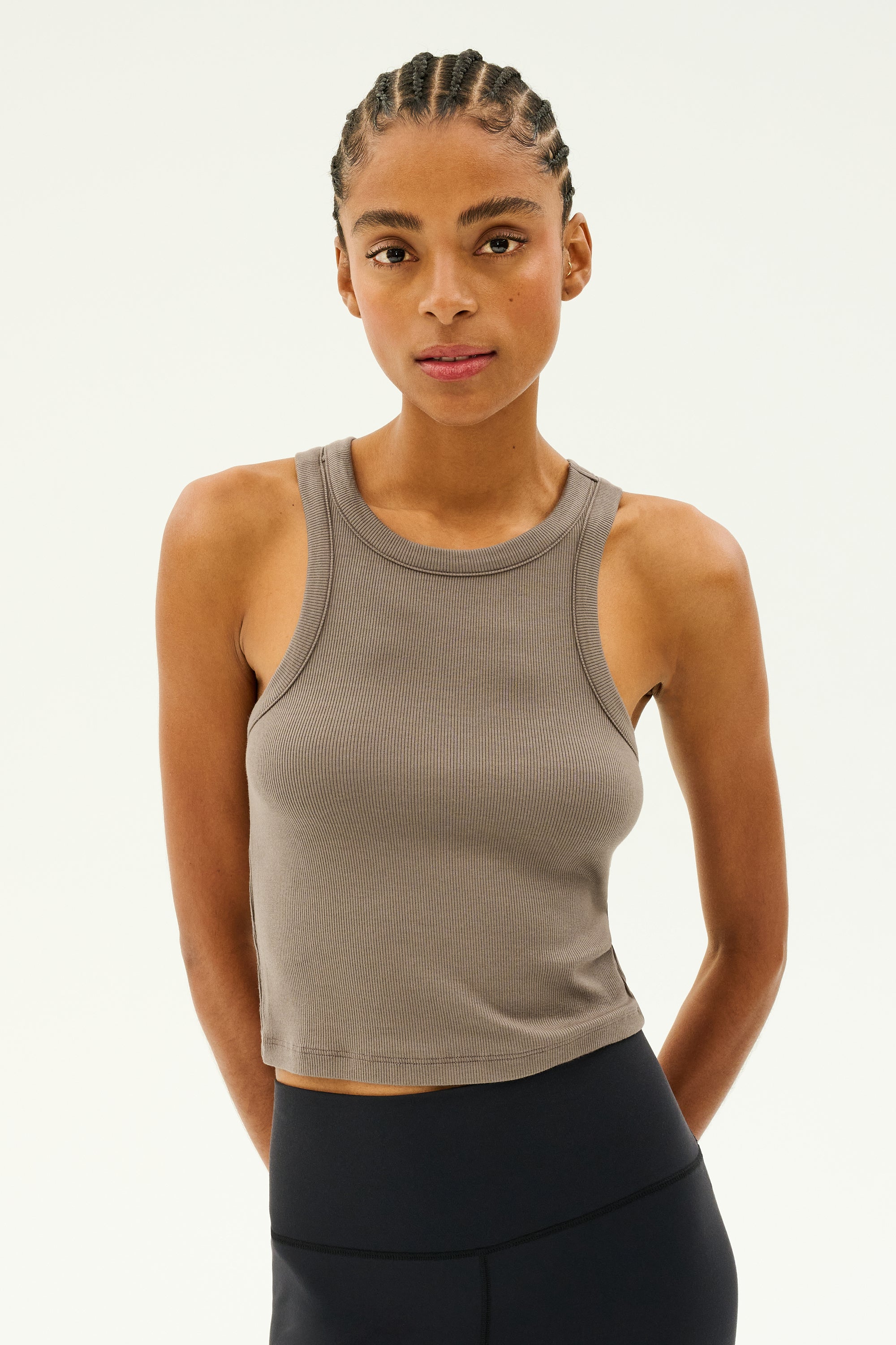 A person wearing the SPLITS59 Kiki Rib Crop in lentil and black leggings, standing against a plain background.