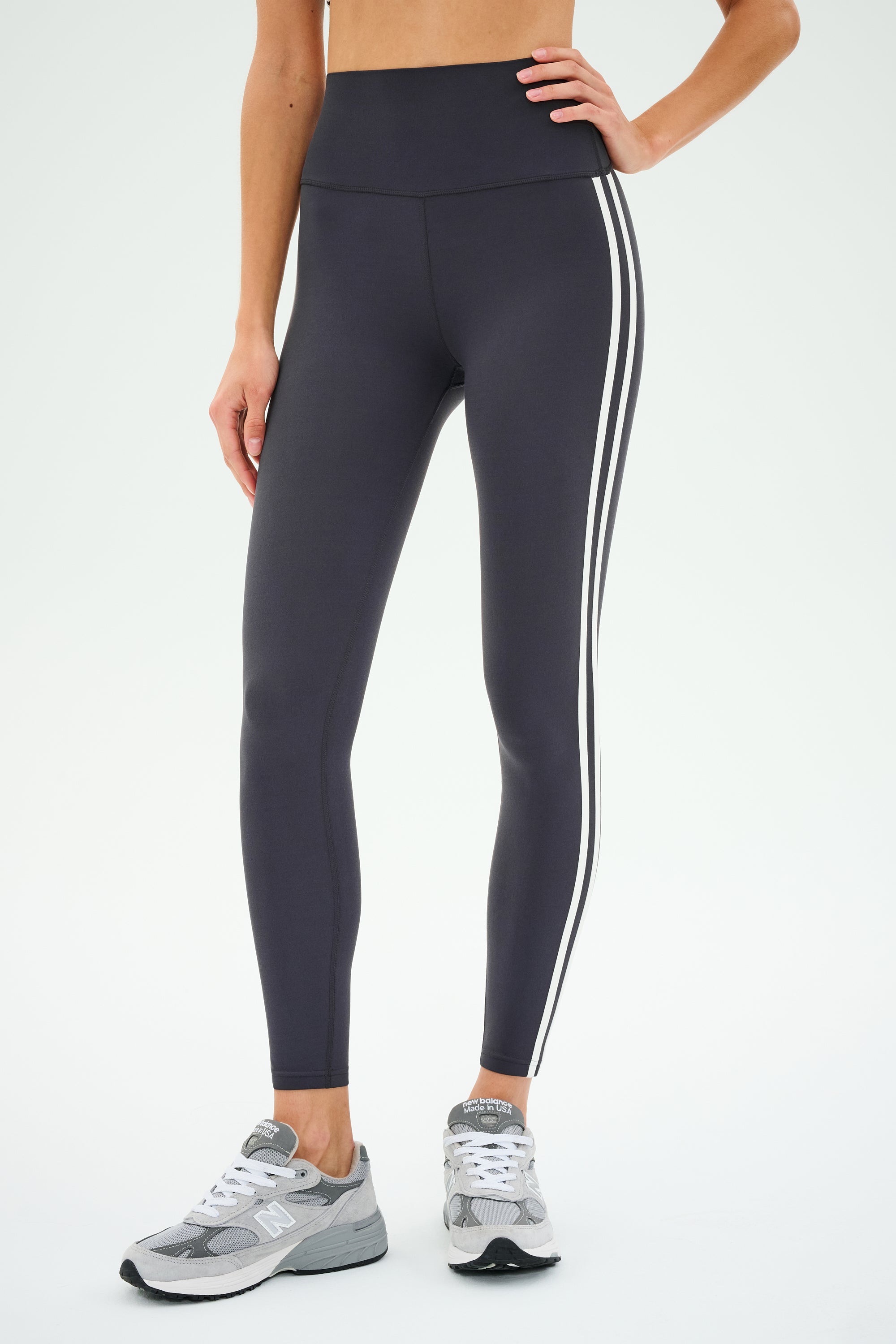 A person is wearing the SPLITS59 Ella High Waist Airweight 7/8 leggings in Graphite/White, paired with gray sneakers.