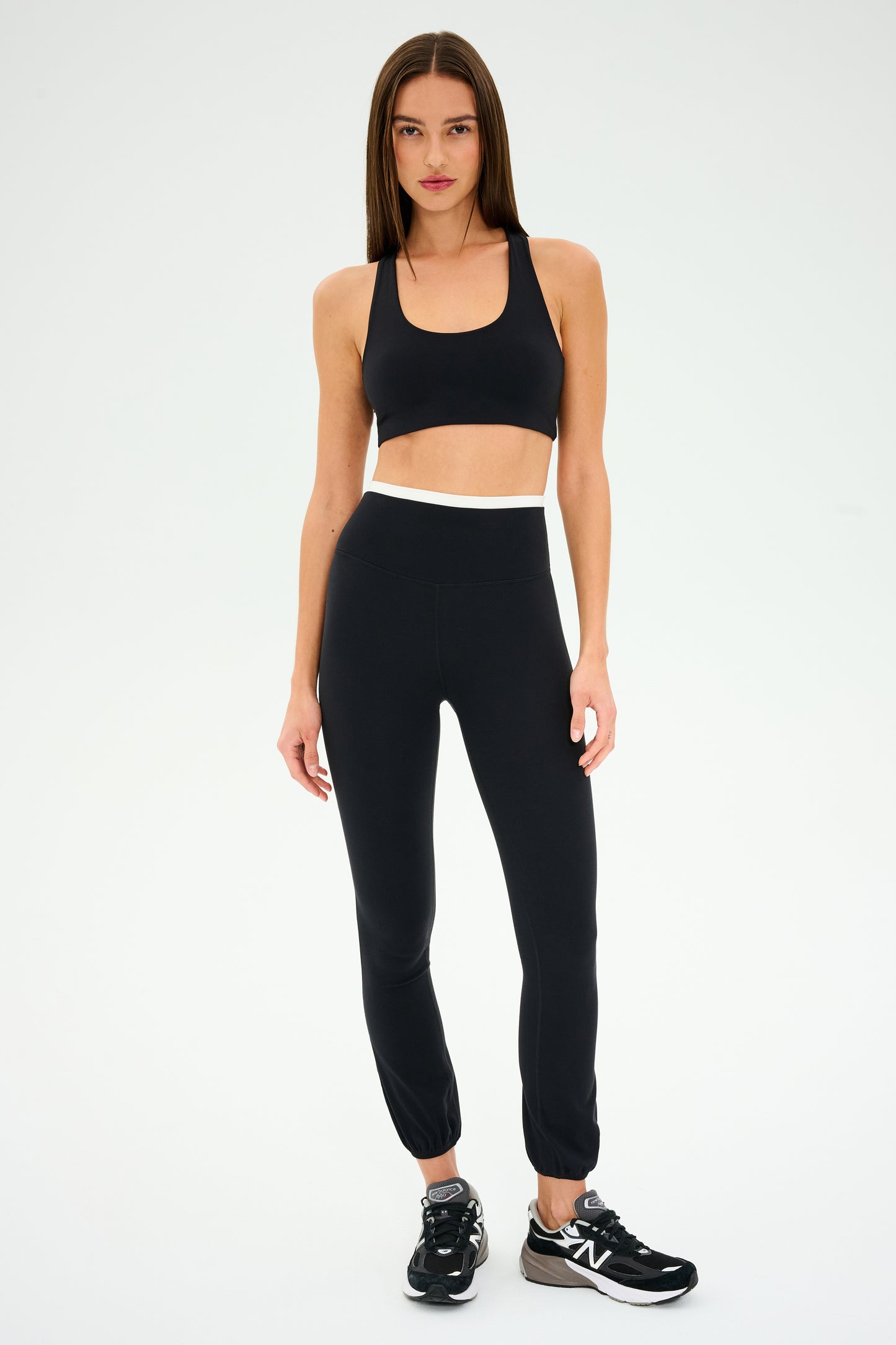 A person stands facing forward wearing the SPLITS59 Icon Dual High Waist Airweight Legging and a black sports bra with black sneakers, against a plain background.