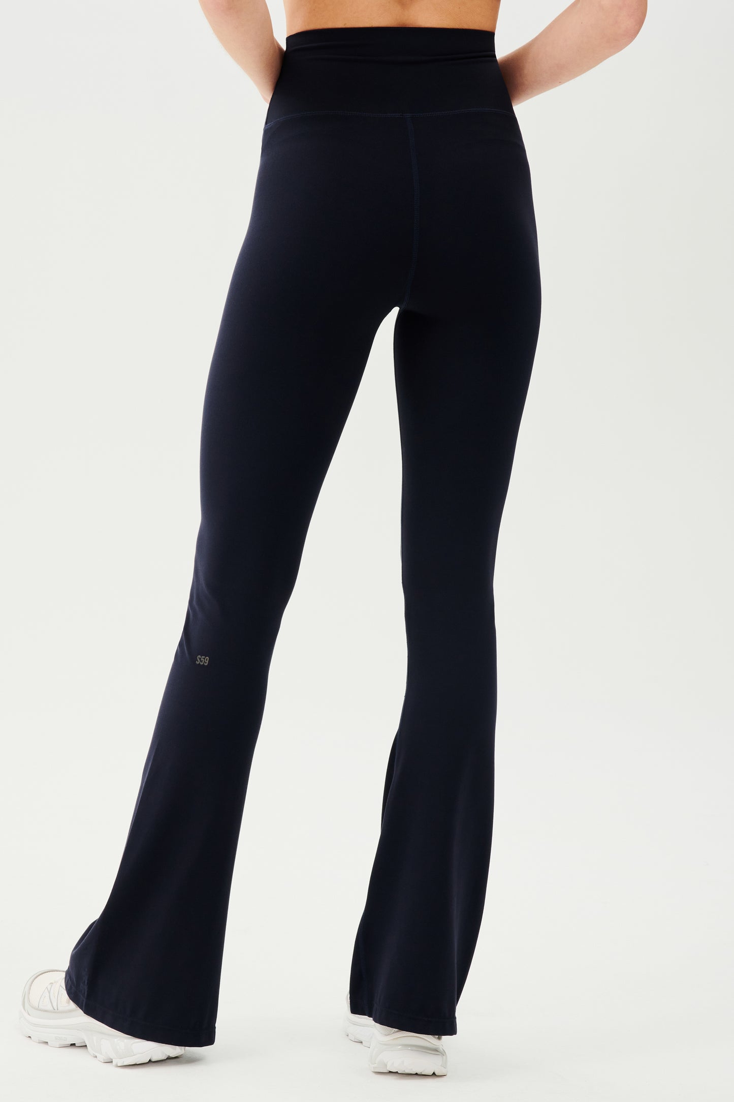 The back view of a woman wearing SPLITS59 Raquel High Waist Airweight Flare - Indigo leggings.