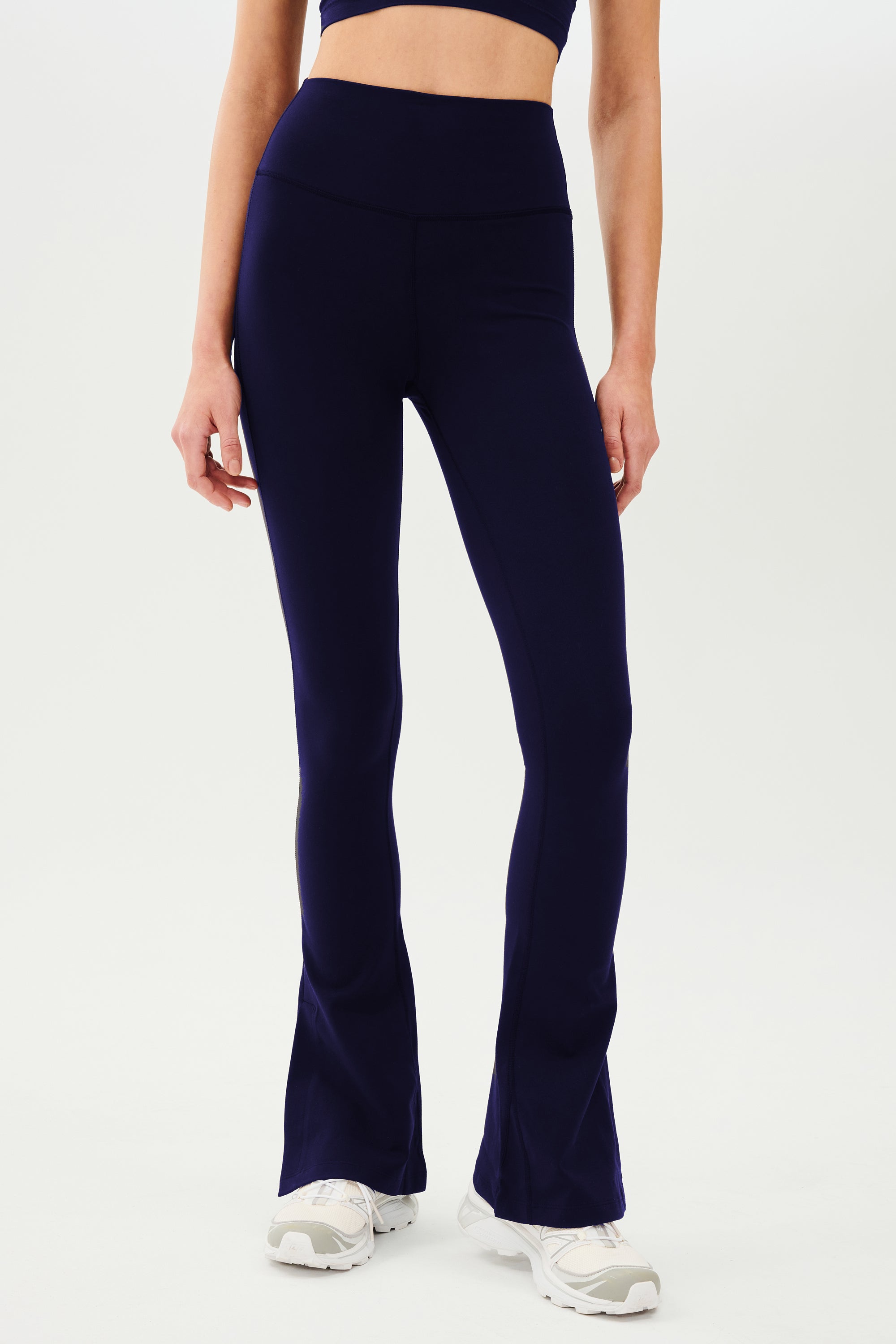 A woman wearing Raquel High Waist Flare w/ Split Hem leggings in indigo from SPLITS59 and a crop top.