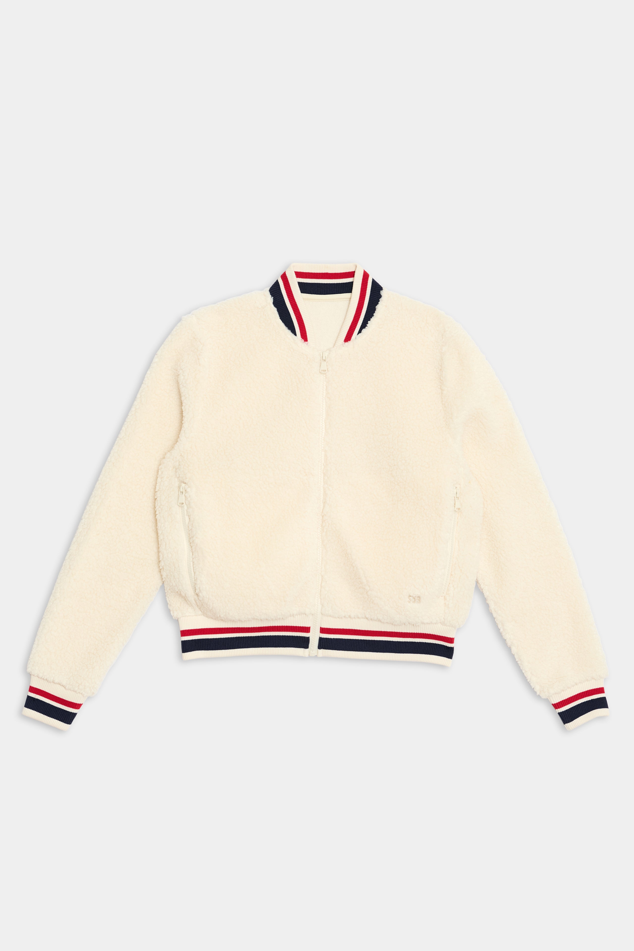 The Willa Sherpa Jacket - Creme by SPLITS59 features a front zipper and striped red, white, and navy ribbed collar, cuffs, and hem. Laid flat against a plain background, it’s perfect for winter workouts or cheering on your favorite sports team.