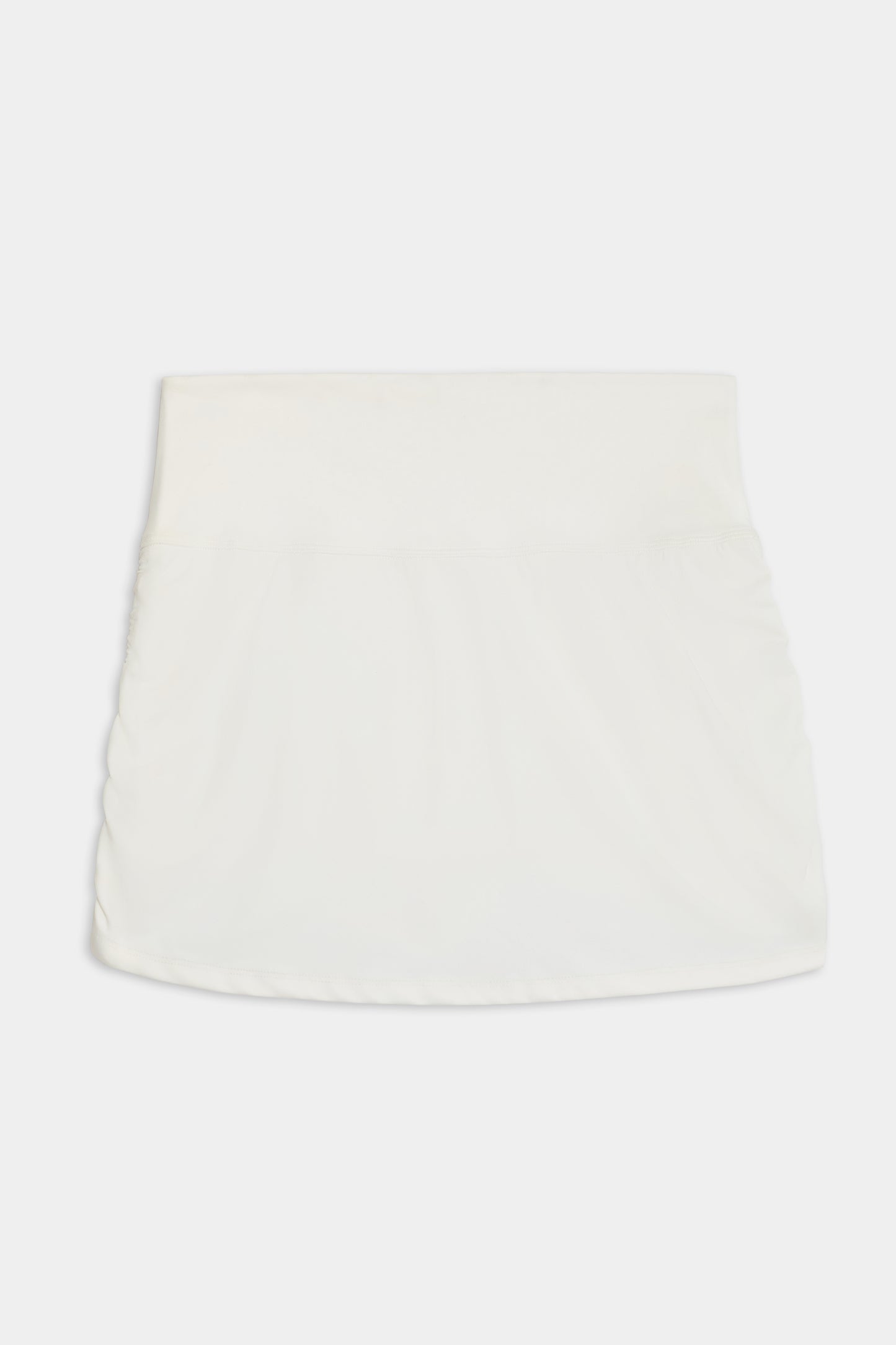 The Sally Rigor Skort by SPLITS59 is a white mini skirt with a simple design and elastic waistband, showcased on a plain background.