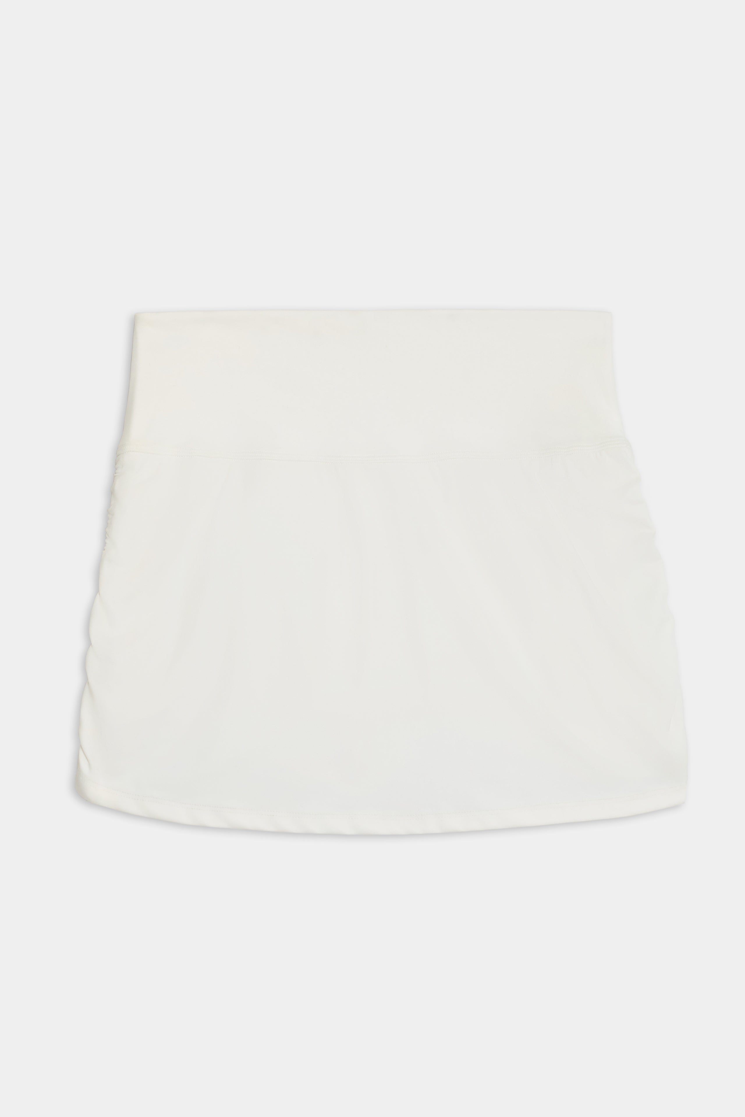 The Sally Rigor Skort by SPLITS59 is a white mini skirt with a simple design and elastic waistband, showcased on a plain background.